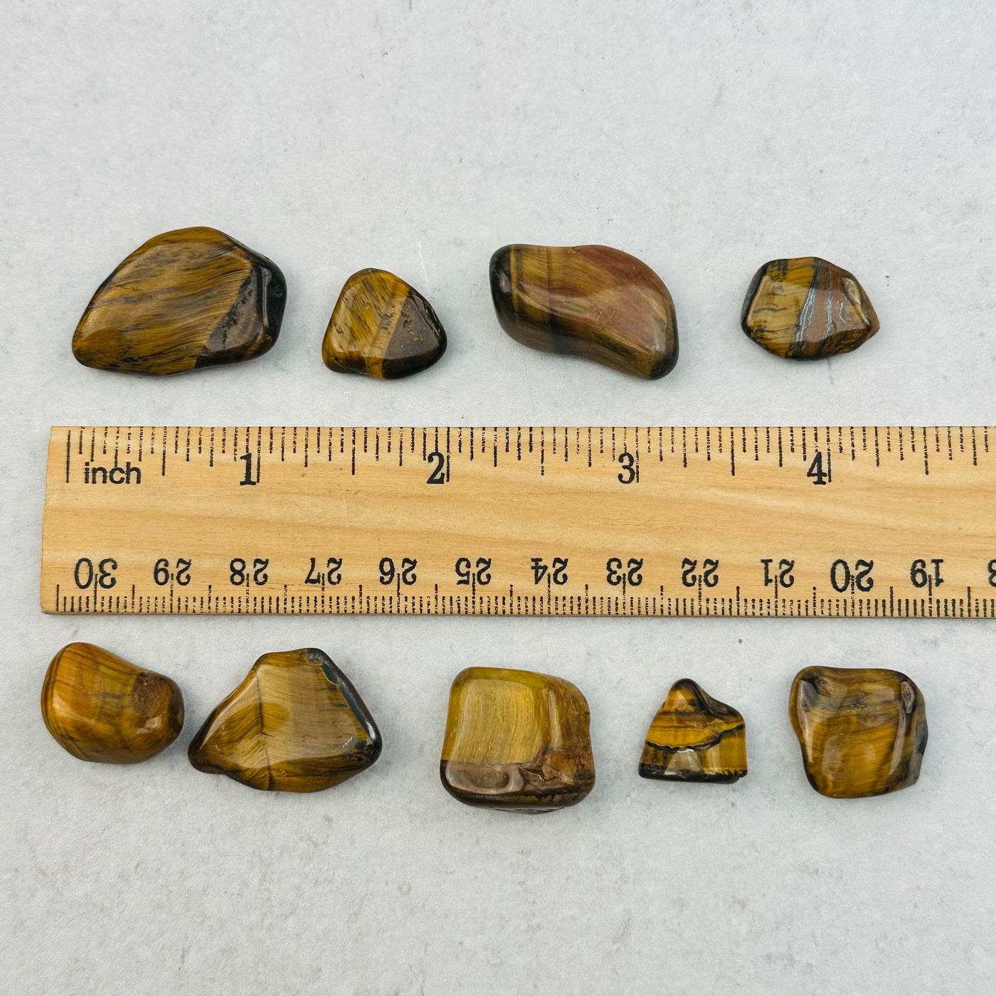tumbled stones next to a ruler for size reference 