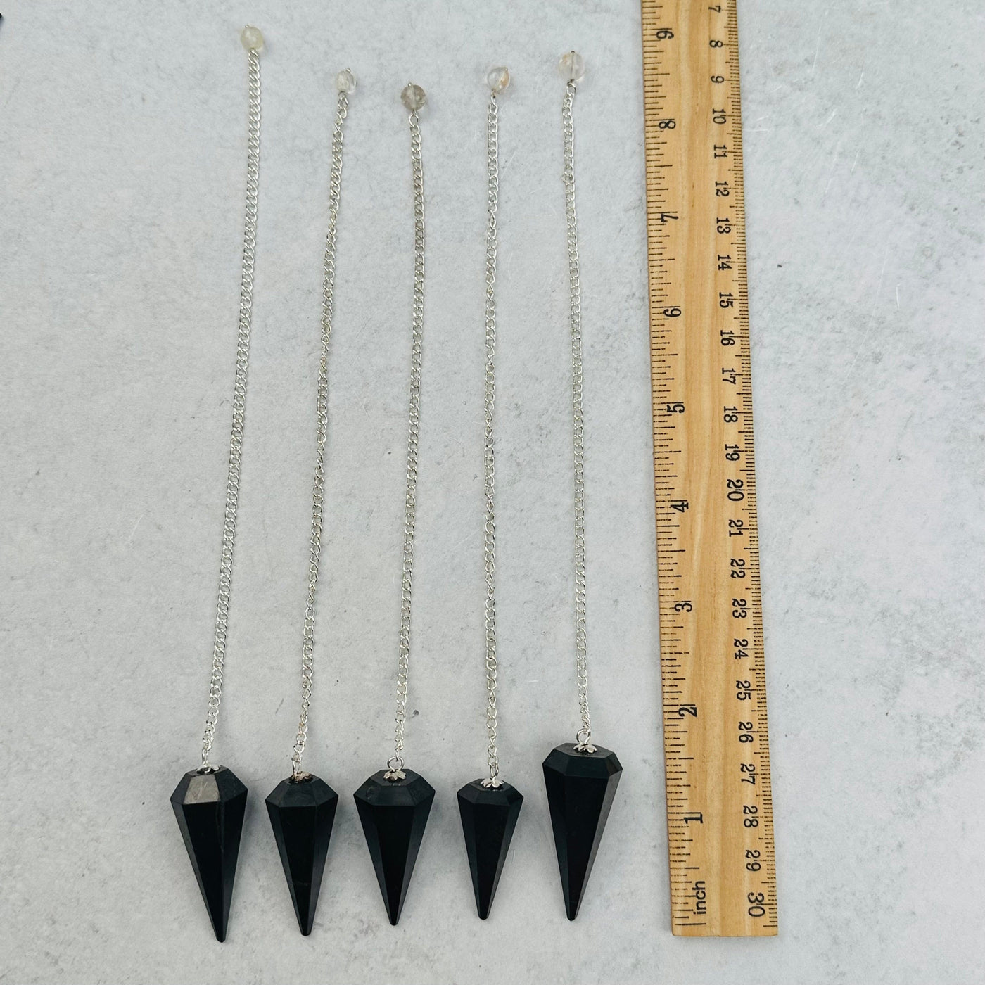 Shungite Pendulums next to a ruler for size reference 