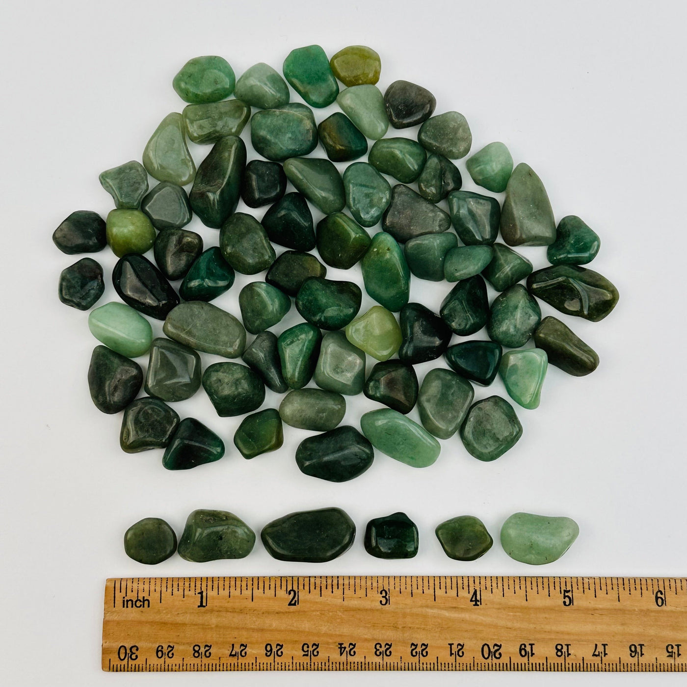 tumbled stones next to a ruler for size reference 