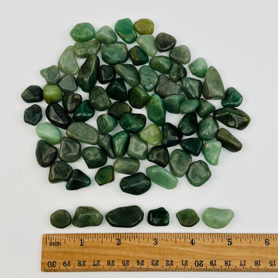 tumbled stones next to a ruler for size reference 
