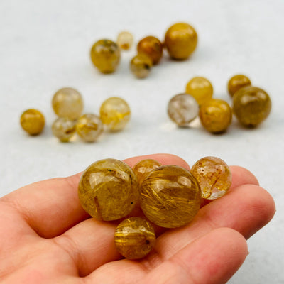 5pc Rutilated Quartz small Spheres in hand for size reference 