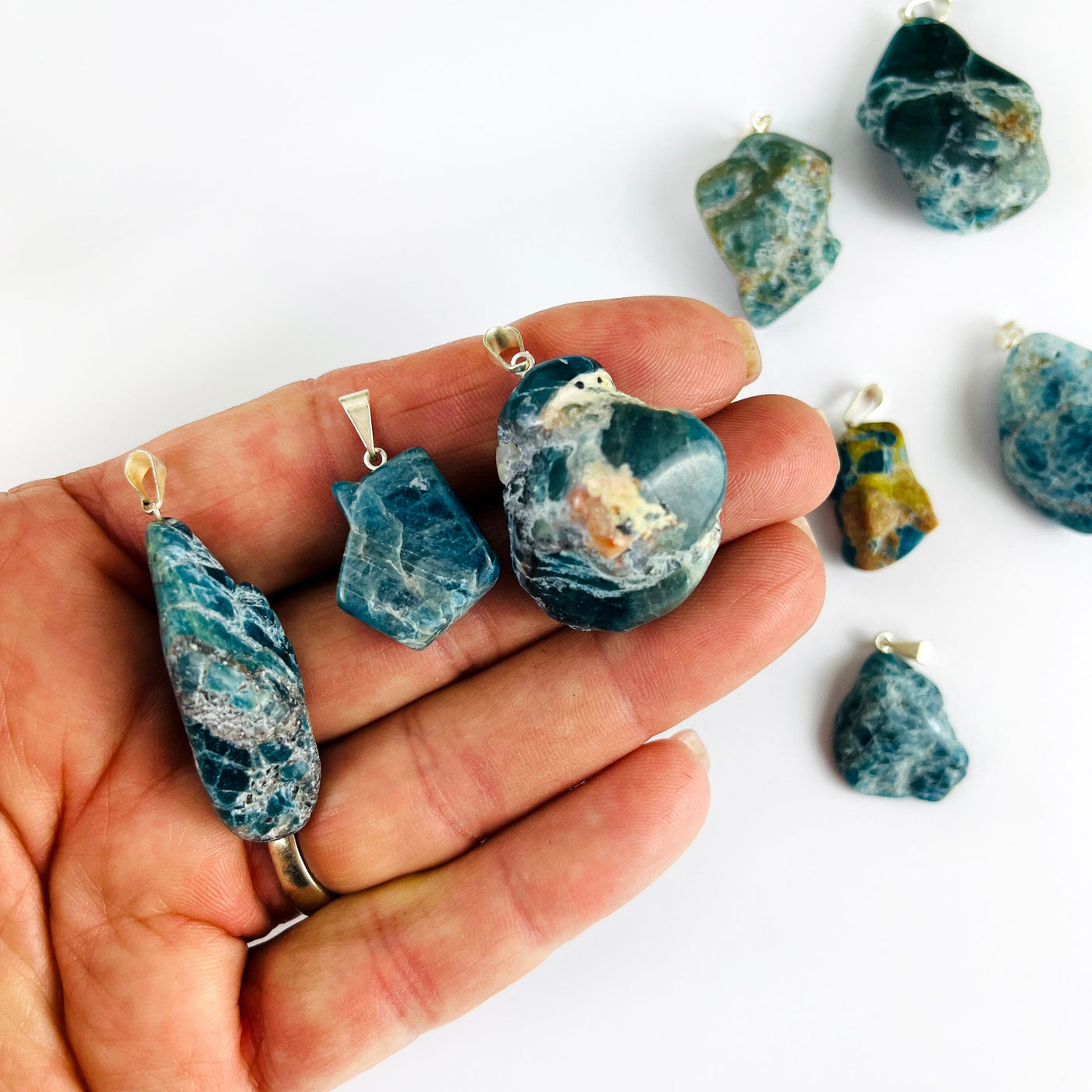 Apatite Polished Freeform Crystal Pendants with Silver Bails in a hand showing various sizes of the stock available