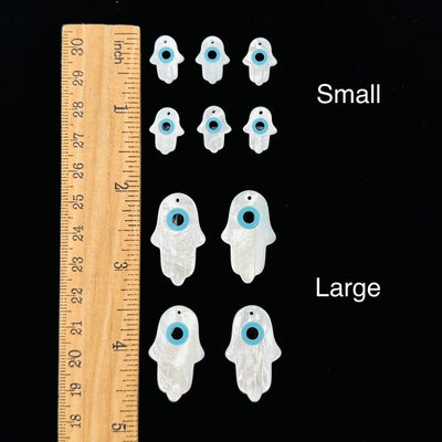 Mother of Pearl Hamsa Hand Eye Drilled Charms displayed next to a ruler for size reference 