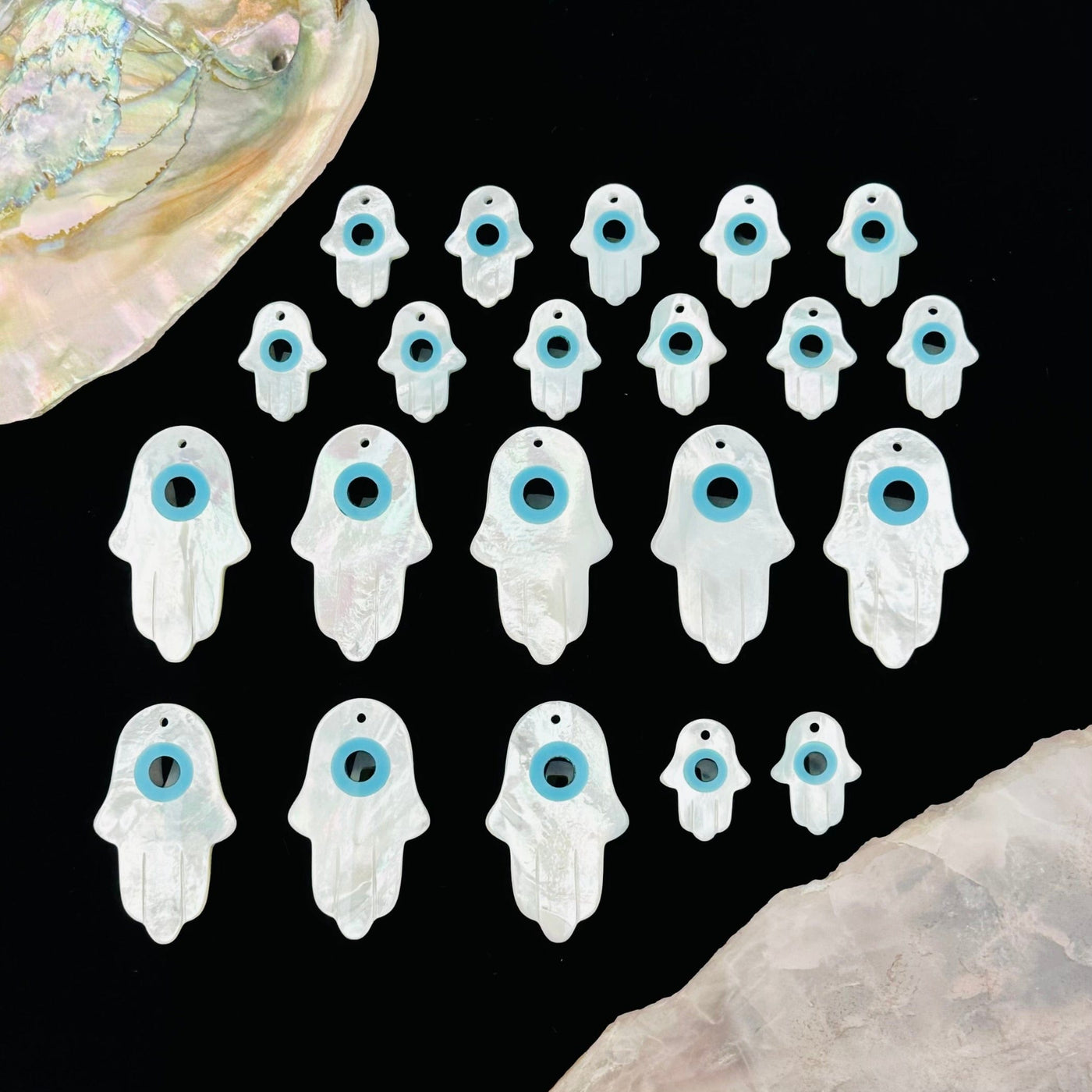 miltiple Mother of Pearl Hamsa Hand Eye Drilled Charms displayed to show the differences in the sizes 