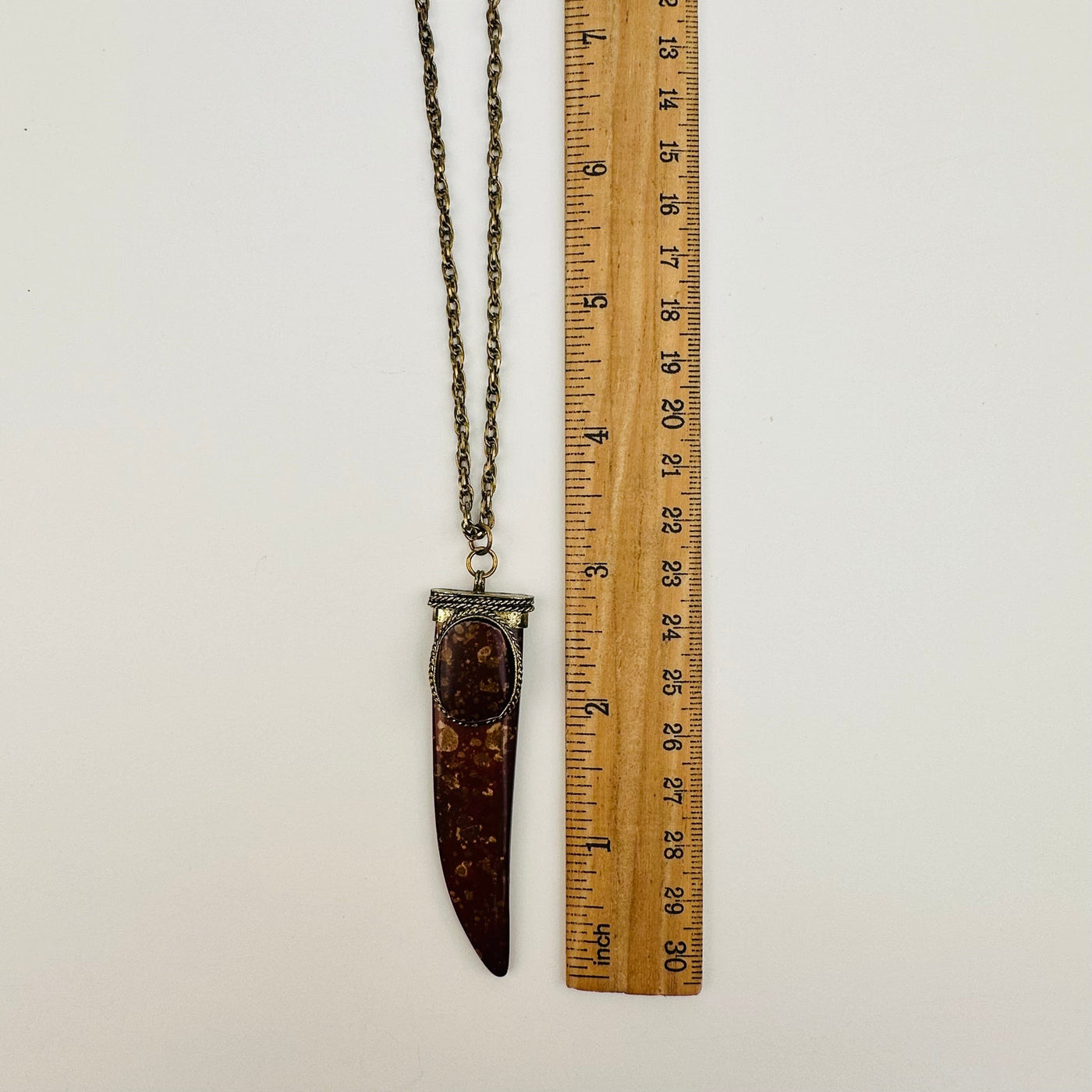 pendant next to a ruler for size reference 