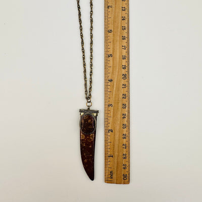 pendant next to a ruler for size reference 