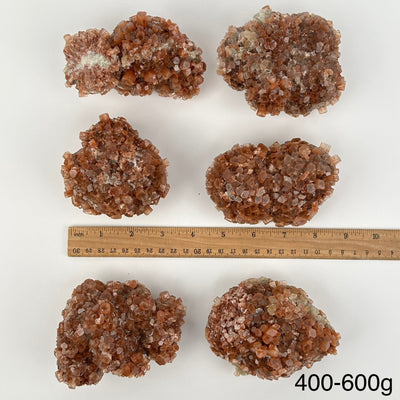 multiple aragonite crystal clusters displayed next to a ruler for size reference 