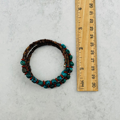 turquoise bracelet with puka shells next to a ruler for size reference