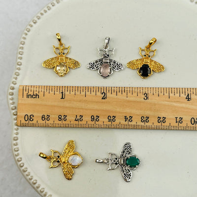 crystal bee pendants next to a ruler for size reference