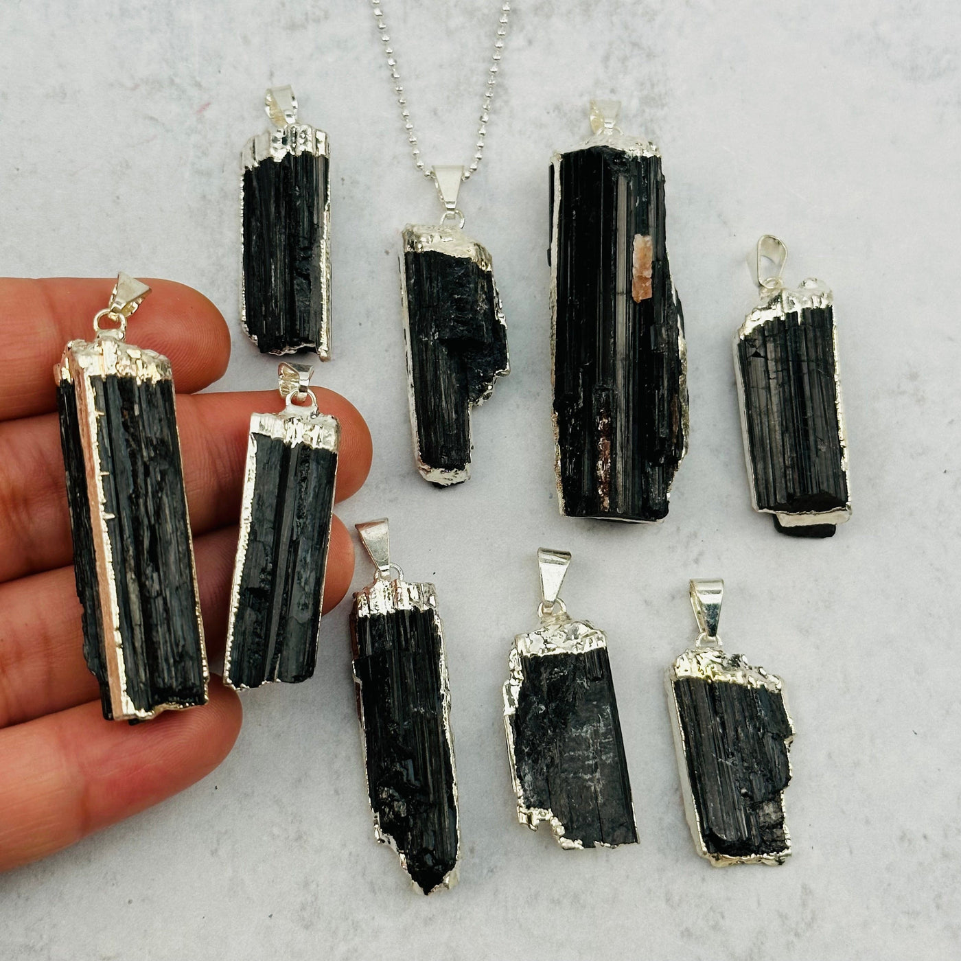 Black Tourmaline Pendant with Electroplated Silver Edges in hand for size reference 