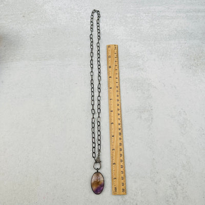 necklace next to a ruler for size reference 