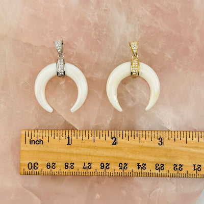 pendants next to a ruler for size reference