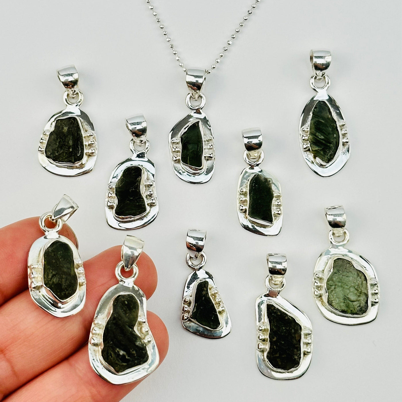 moldavite pendants in hand for size reference 