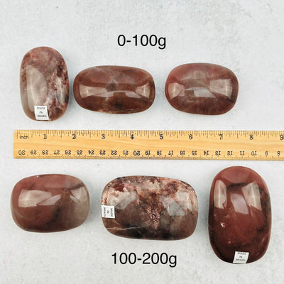 Guava Quartz Crystal Palm Stones next to a ruler for size reference 