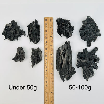 Black Kyanite Crystal Clusters by weight next to a ruler for size reference 