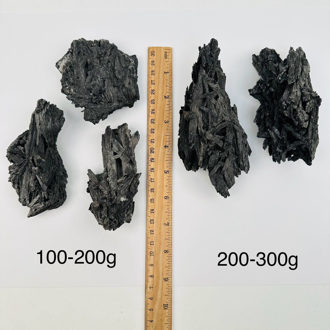 Black Kyanite Crystal Clusters by weight next to a ruler for size reference