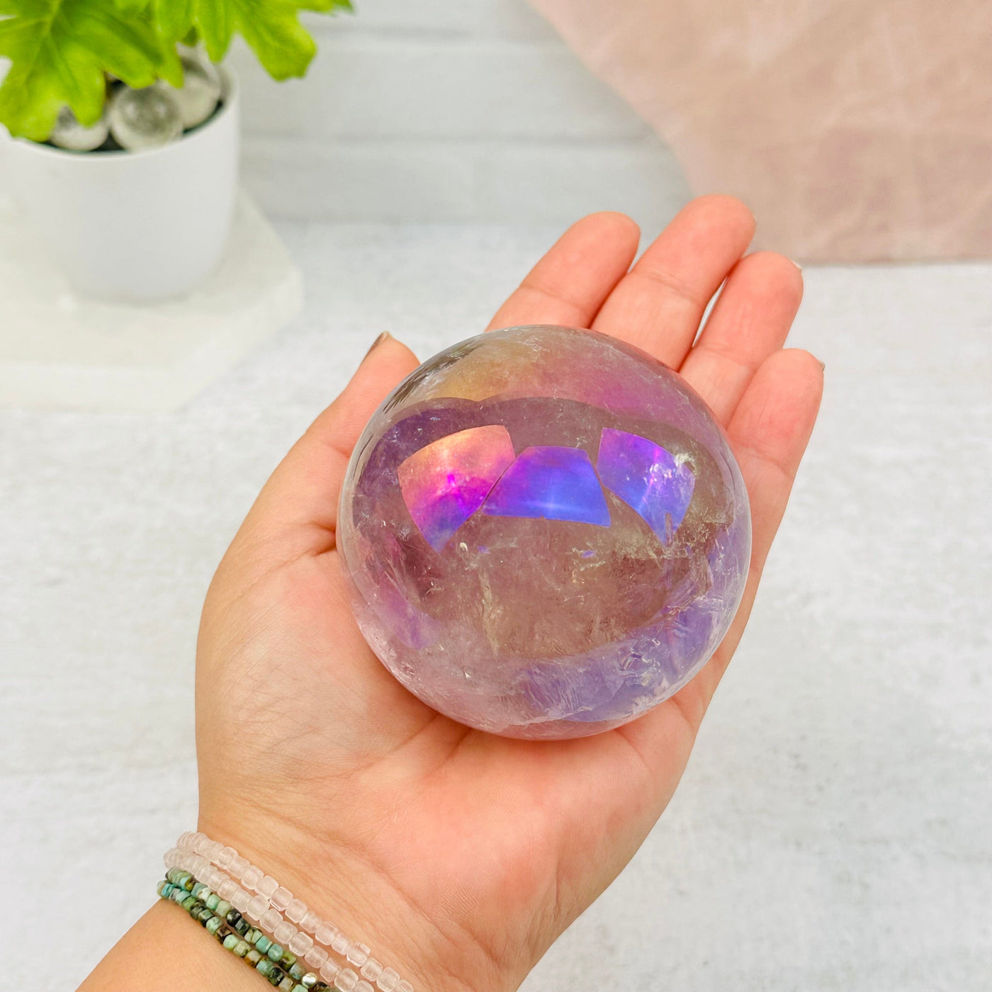 Angel Aura Amethyst Polished Sphere in hand for size reference 