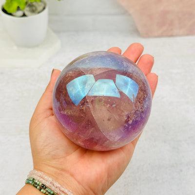 Angel Aura Amethyst Polished Sphere in hand for size reference
