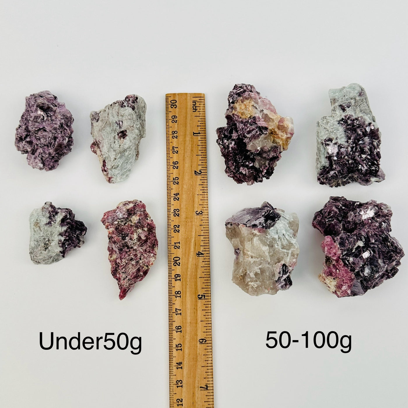 lepidolite unicorn crystal clusters are sold by weight. displayed next to a ruler for size reference