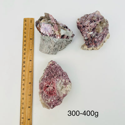 lepidolite unicorn crystal clusters are sold by weight. displayed next to a ruler for size reference