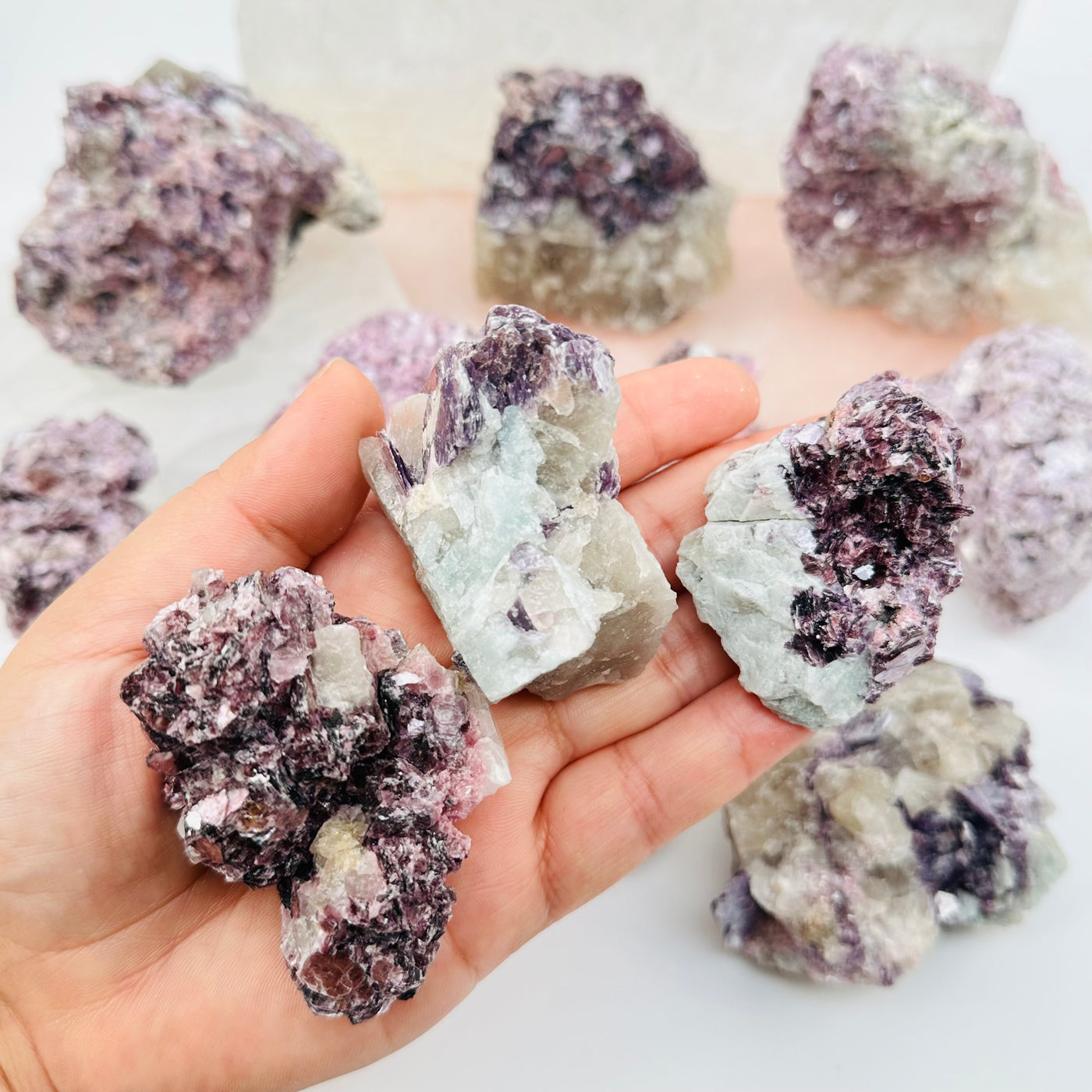 lepidolite unicorn crystal clusters in hand for size reference 