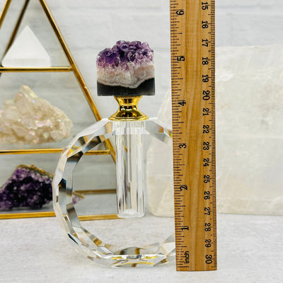 crystal bottle next to a ruler for size reference 