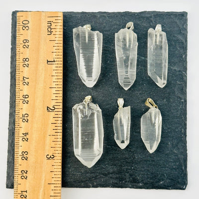 lemurian pendants next to a ruler for size reference 