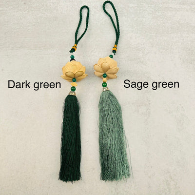 sage green and dark green tassels displayed next to each other to show the differences in the color shades wooden lotus flower tassel with decorations in the background