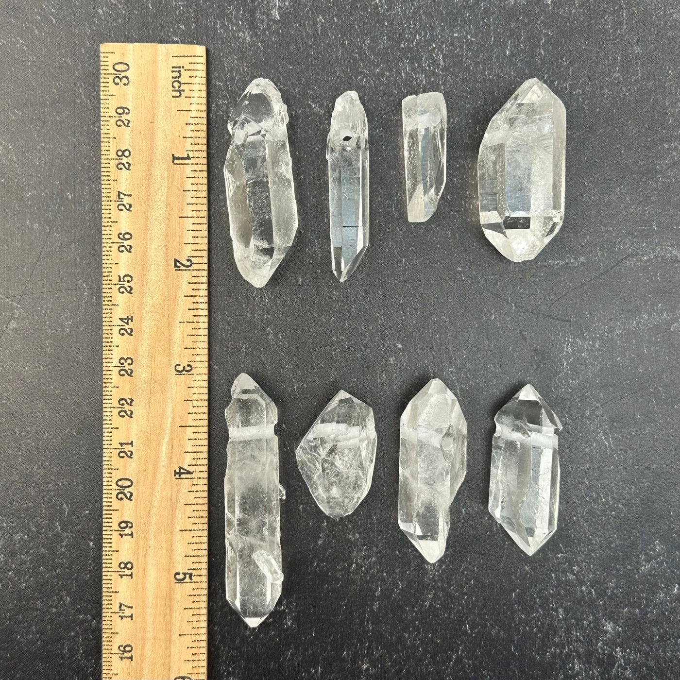 top drilled crystal quartz pendants next to a ruler for size reference  