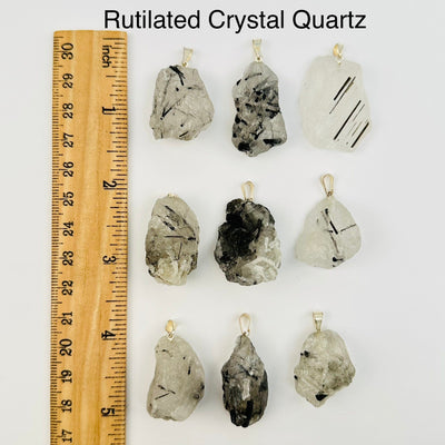 rutilated quartz pendants next to a ruler for size reference 