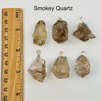 smokey quartz pendants next to a ruler for size reference 