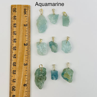 aquamarine pendants next to a ruler for size reference 