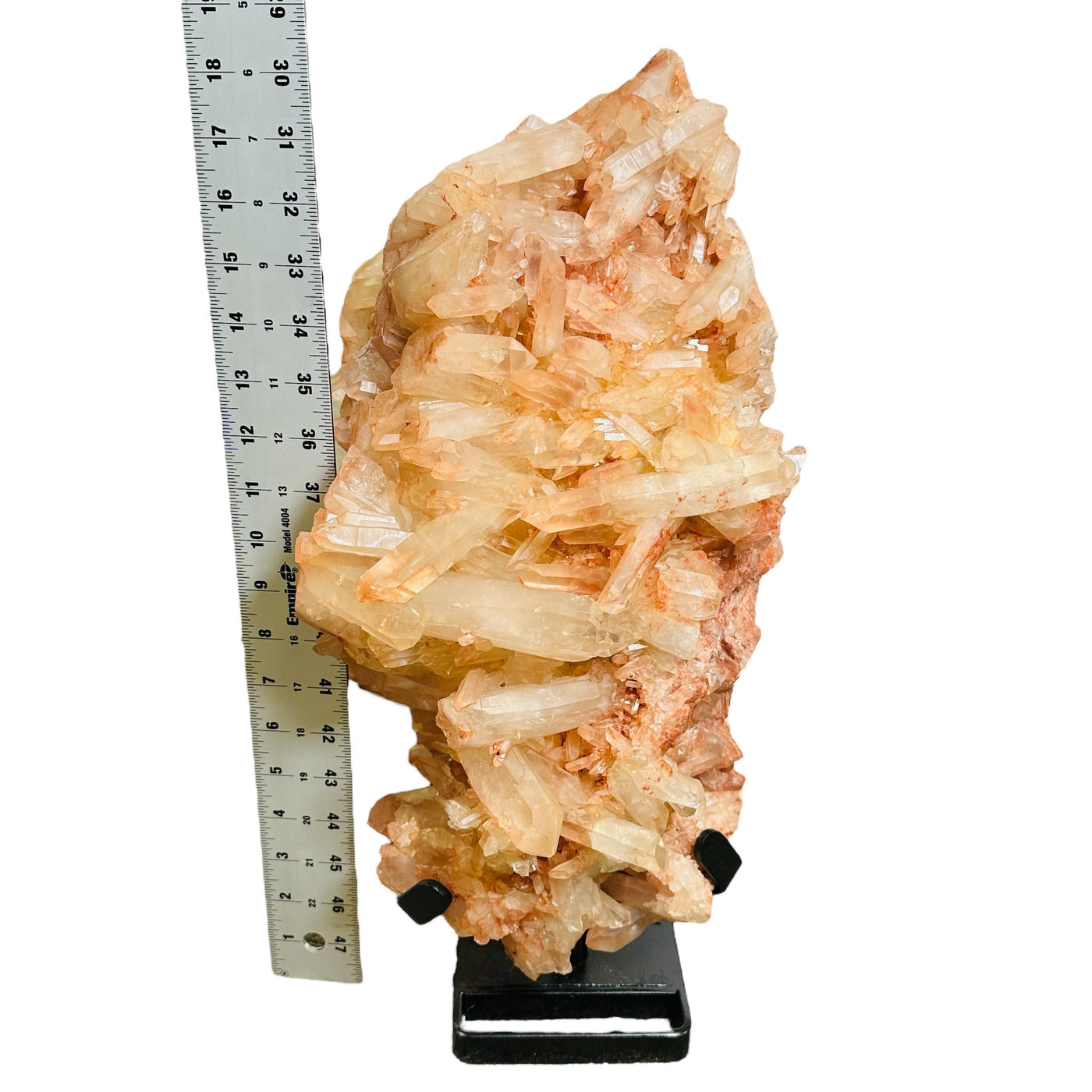 tangerine crystal quartz cluster on stand next to a ruler for size reference 