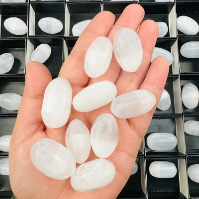 multiple oval selenite pieces in hand for size reference 