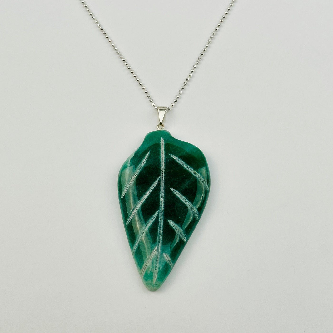 leaf pendant displayed on a necklace to show how it hangs