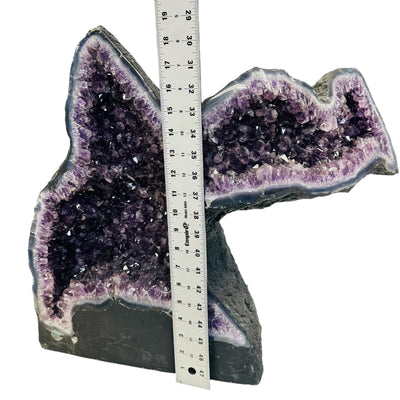 right side of the amethyst geode displayed next to a ruler for size reference 