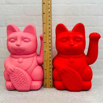 lucky cat next to a ruler for size reference 