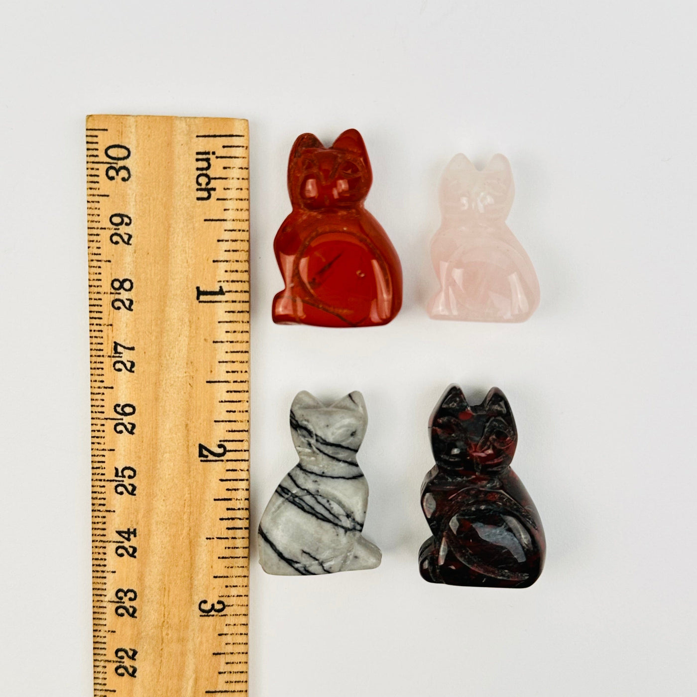 gemstone cats next to a ruler for size reference 