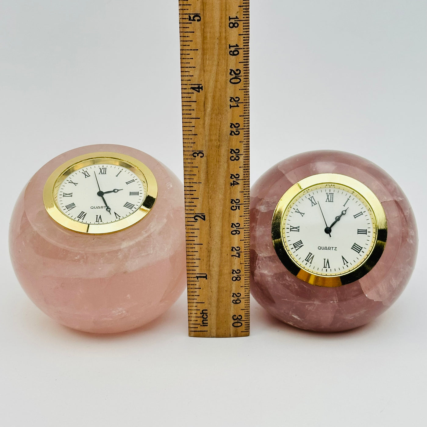 rose quartz crystal clocks displayed next to a ruler for size reference 