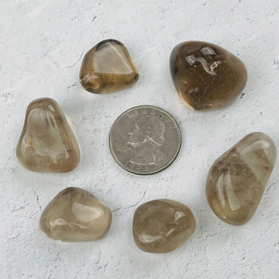tumbled stones next to a quarter for size reference 