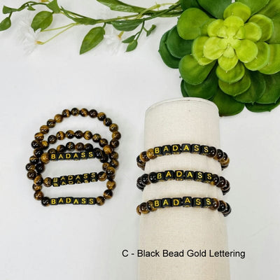 black with Gold print "BADASS" letter beads on on display