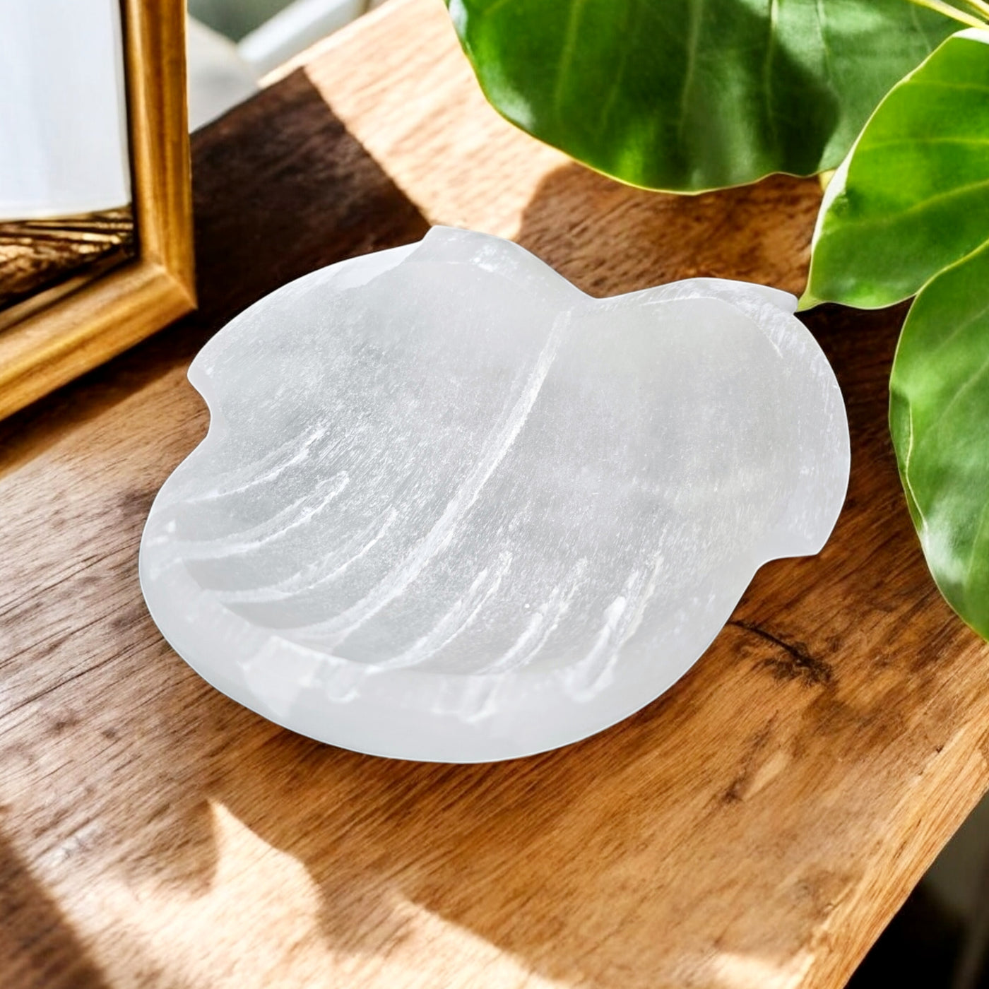 Selenite Hands Crystal Bowl 3/4 angle view on wooden table with plants and props in the background