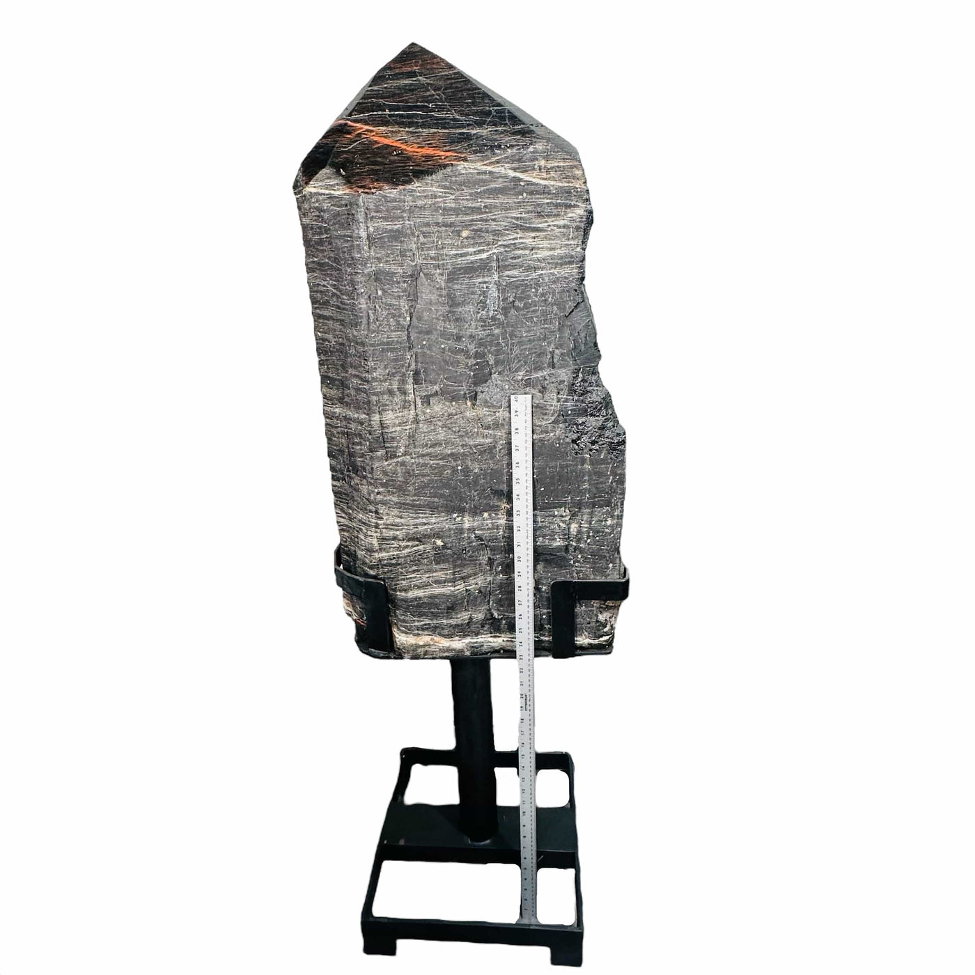 large black tourmaline on a metal stand with a tape measure on it showing it is larger.