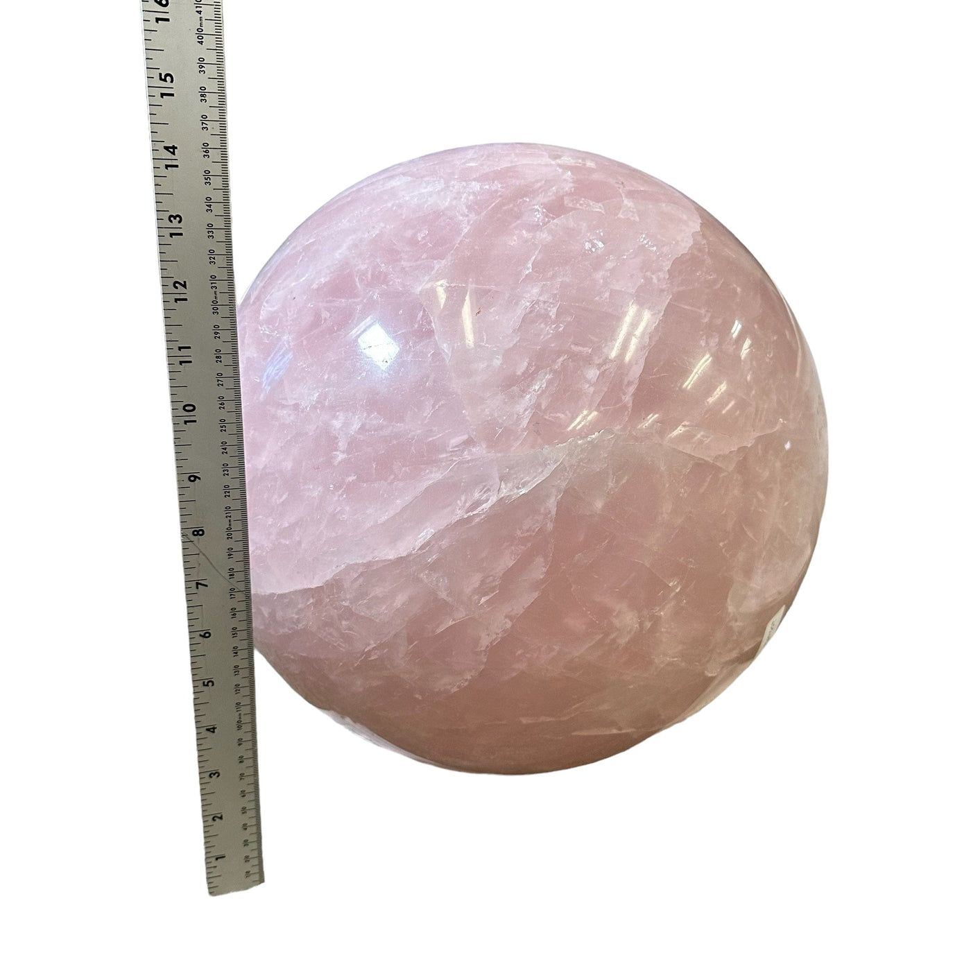 rose quartz sphere next to a ruler for size reference 