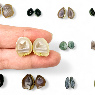 Tiny Agate Druzy Crystal Geode Pair - You Choose - variant 87 in hand for size reference with other pairs in the background on a white surface