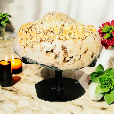 High-Grade Pink Amethyst Crystal Geode on Rotating Stand on marble countertop with succulents and candles