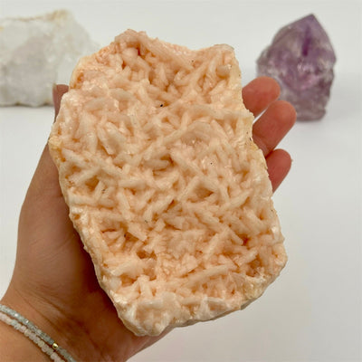 pink dolomite crystal cluster in hand for size reference 