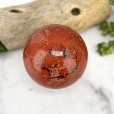 red jasper sphere with decorations in the background