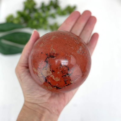 red jasper sphere with decorations in the background