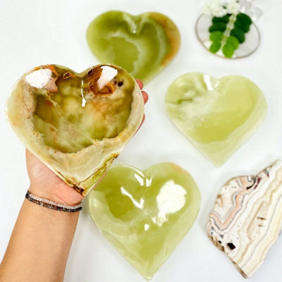 Green Mexican Onyx Heart Bowls with one in a hand for size reference, showing also color variances

